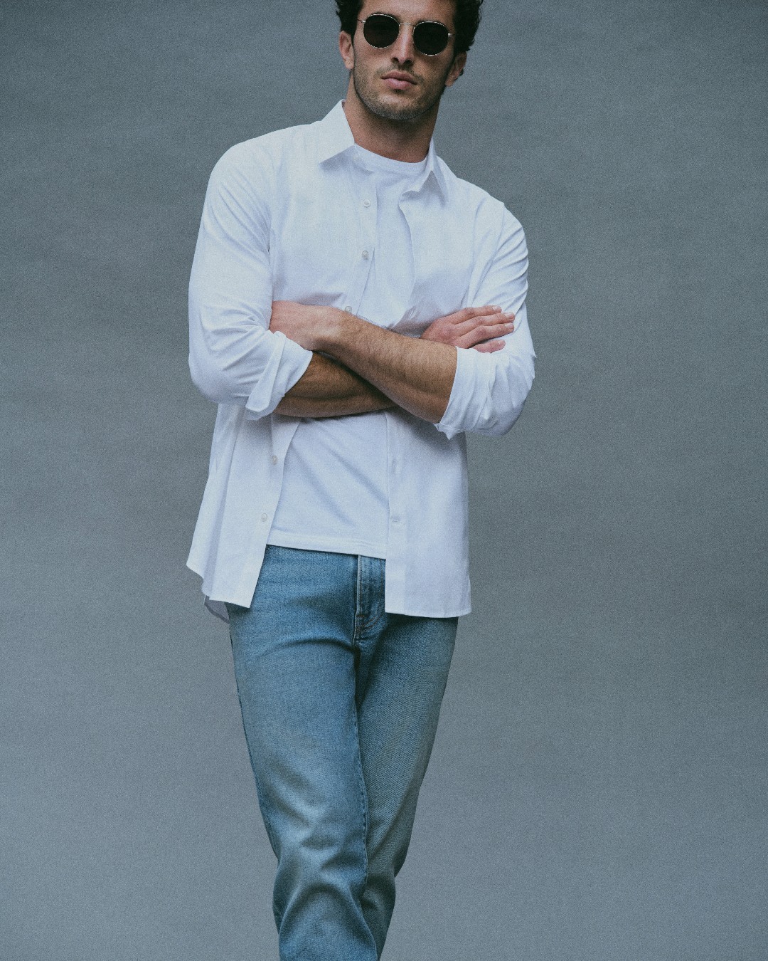 459321343_1082184093313943_925976550338823585_n model in sunglasses jeans and a dress shirt standing